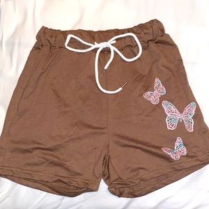 Brown high-waisted shorts, with butterflies on the leg.